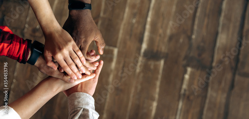 Stack of hands. Top view of a successful business team which puts their hands together over a wooden background. Unity and teamwork concept. Copy space