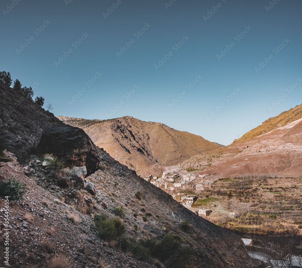 Sunrise in the high Atlas mountains in Morocco near small village of imlil. Blue sky and hiking path. Houses in the background. Travel conept during summer.