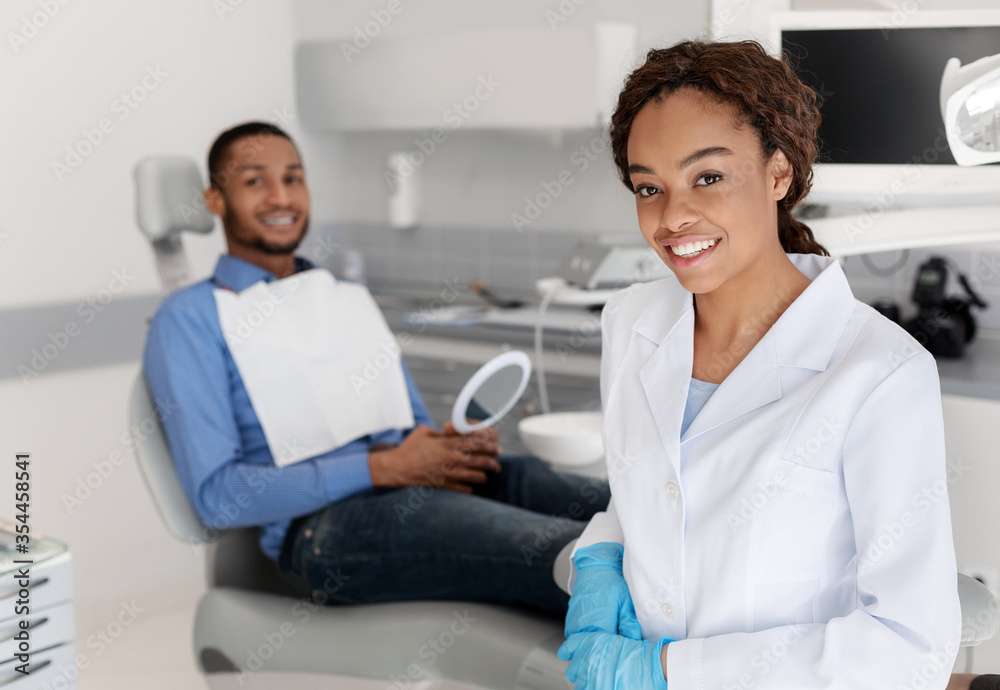 Smiling dentist and patient looking at camera, dental cabinet interior Smiling dentist and patient looking at camera, dental cabinet interior