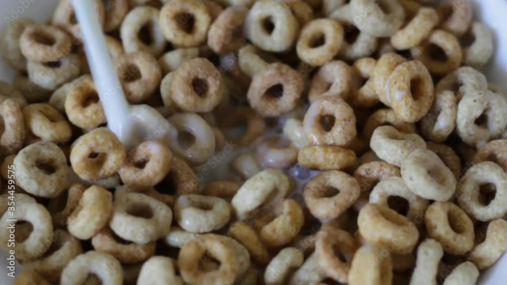 Closeup of pouring Milk into round cereal in white bowl. Closeup of pouring Milk into round cereal in white bowl.