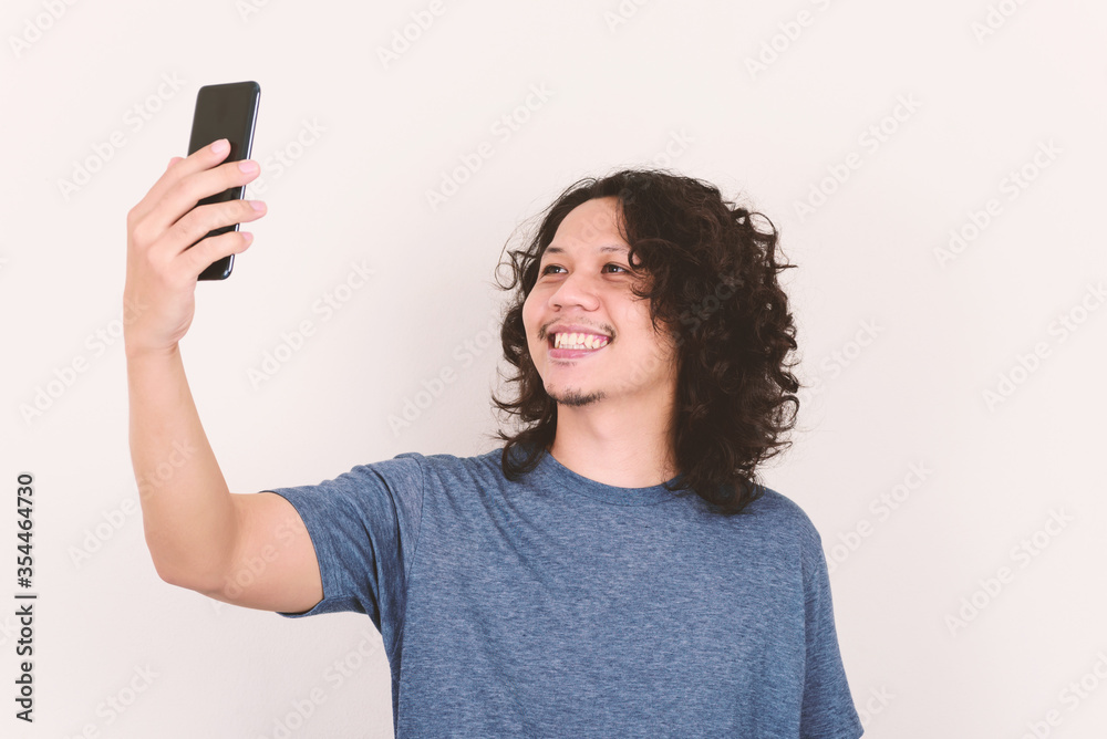 Portrait of Asian man smiling and holding mobile phone for selfie, video call or playing social media Portrait of Asian man smiling and holding mobile phone for selfie, video call or playing social media