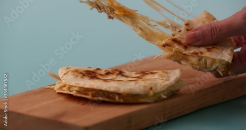 Putting a tortilla in a skillet adding shredded cheese, a slice of cheese, chicken on a second tortilla to prepare a quesadilla and serving it