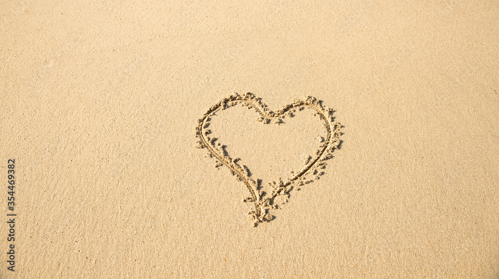 heart drawn in the sand on the beach. Romantic design element.