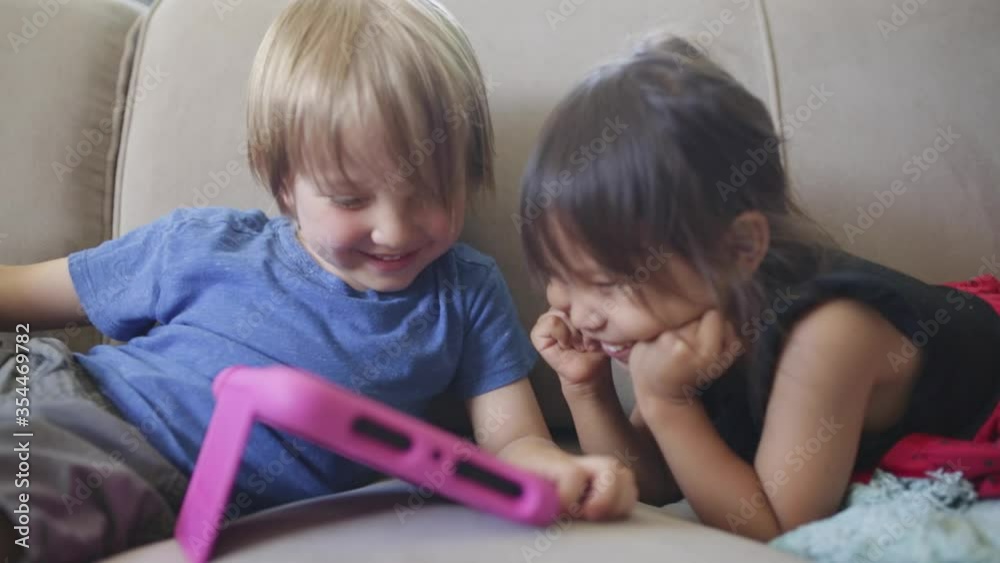 Caucasian boy and Asian girl play and learn on electronic tablet device Caucasian boy and Asian girl play and learn on electronic tablet device