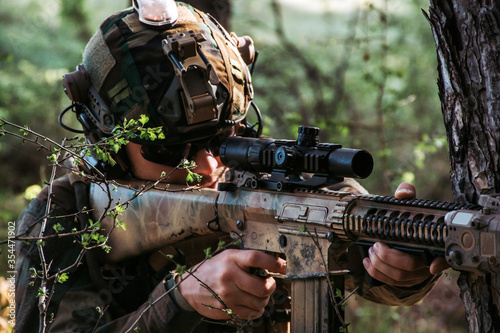 Soldier in a forest hiding in a foliage. Full equipment. soldier aiming with gun in forest. soldier concept photo