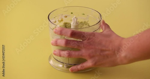 Putting chickpeas, avocado, salt, pepper, cilantro, olive oil and pouring lime juice in a blender to prepare avocado hummus