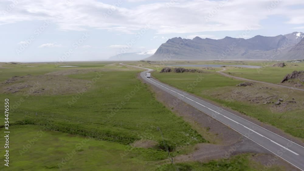 Aerial shot of camper van moving on road along green landscape, drone is flying forward - Southwestern Iceland, Iceland Aerial shot of camper van moving on road along green landscape, drone is flying forward - Southwestern Iceland, Iceland