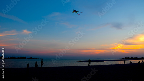 Silhouette of a man playing kite during sunset. © yahya