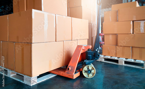 Stack of shipment boxes on pallet and hand pallet truck. Interior of warehouse storage, warehouse industry delivery shpping goods, logistics and transport.