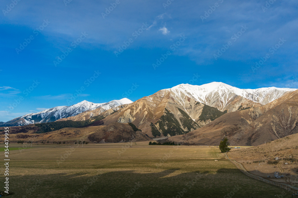 Mountain countryside landscape with csnoq-capped mountains and green farmlands Mountain countryside landscape with csnoq-capped mountains and green farmlands