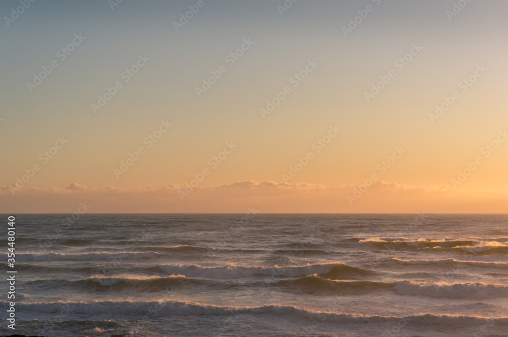 Tranquil ocean sunset seascape with soft clouds and waves