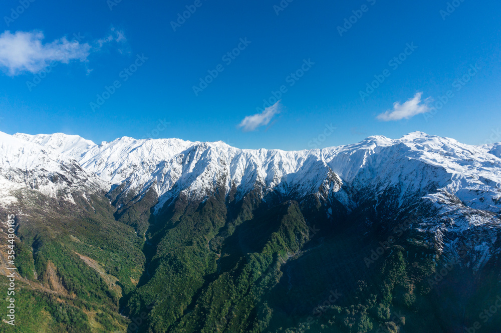 Winter mountain landscape with green slopes and snow covered peaks