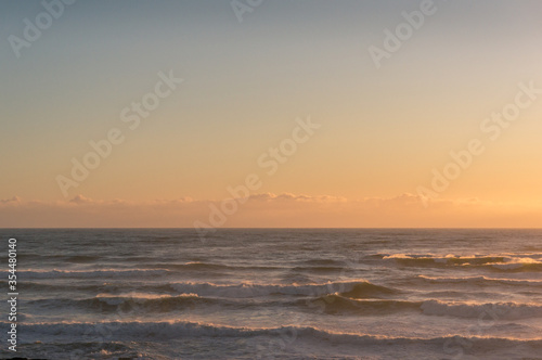 Tranquil ocean sunset seascape with soft clouds and waves © Olga K