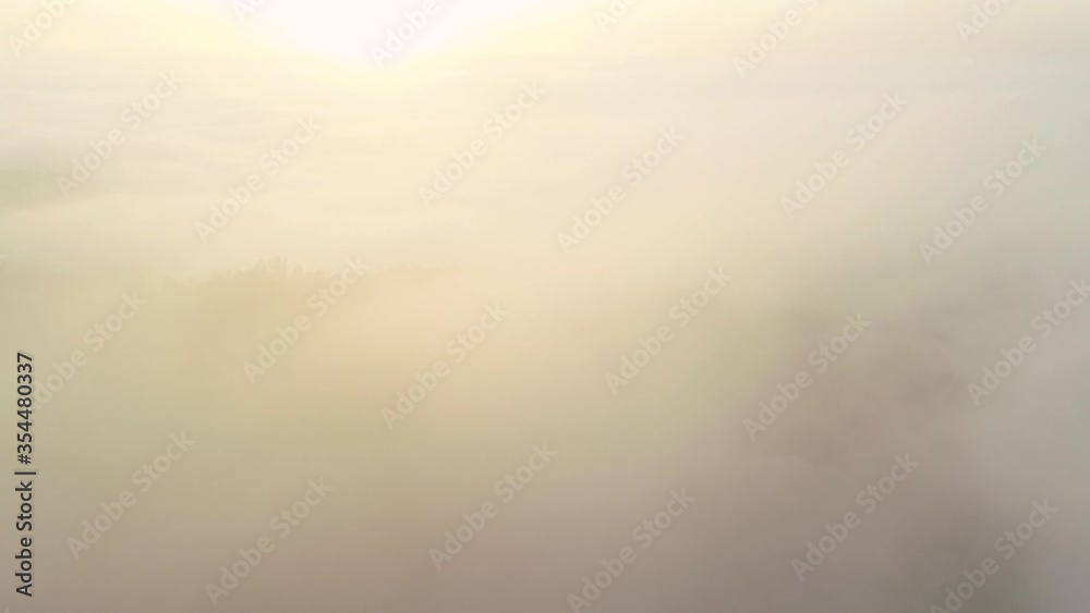 Backward flight above blanket of clouds with large bright white sun on horizon, pull back aerial Backward flight above blanket of clouds with large bright white sun on horizon, pull back aerial