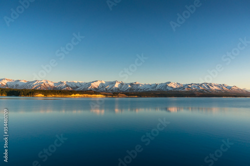Sunrise winter mountains landscape with calm lake and water reflections