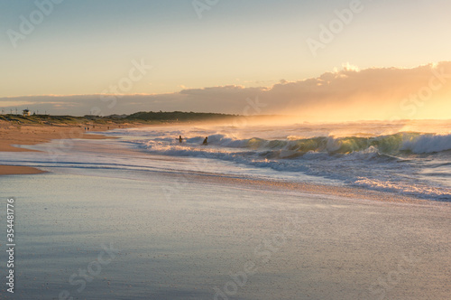 Summer beach background with beautiful waves and surfers in the distance