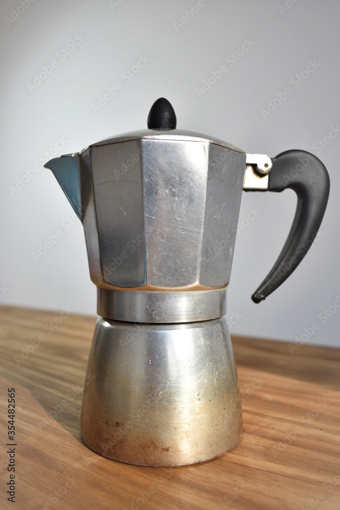 a metal coffee maker on a wood table a metal coffee maker on a wood table