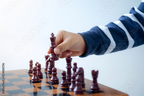 Hand of boy playing chess, image of kids hand moving one of the pieces