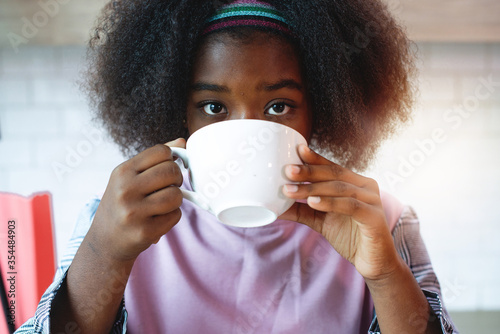 Close-up of dark skinned teenage girls drinking coffee, looking at camera