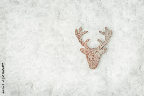 Head and antlers of deer, wooden toy fot christmas tree. Figure of deer on white snow. Christmas decoration. Holiday winter background.