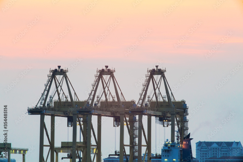 Crane for shipping container carrier with sunrise background
