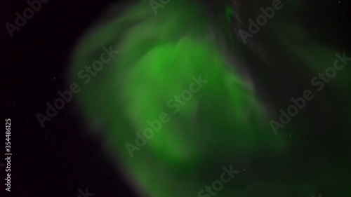 Creative moving shot of northern lights, iceland, mostly green with some pink. Interesting circular shaped lights. photo