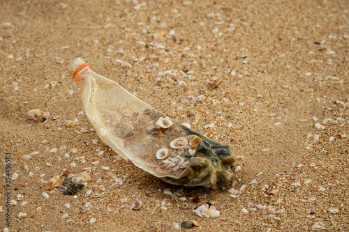 Rubbish Plastic PET bottle laying on sandy beach full of seashells. Environment and ocean pollution. Garbage on the beach. Climate change photo