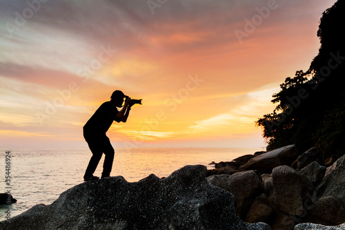 Silhouette view of male model photographer by sunrise or sunset background 