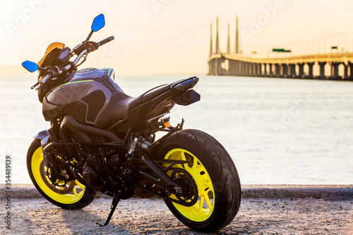 A black motorbike parking by the shore of Penang Bridge photo