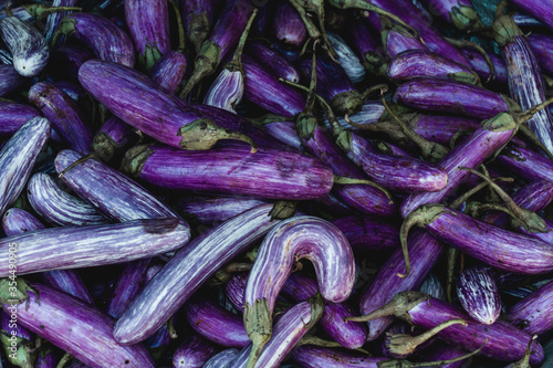Pile of fresh eggplant on fruit market stall. Local produce. Seasonal harvest. Vegan & vegetarian food. Violet color