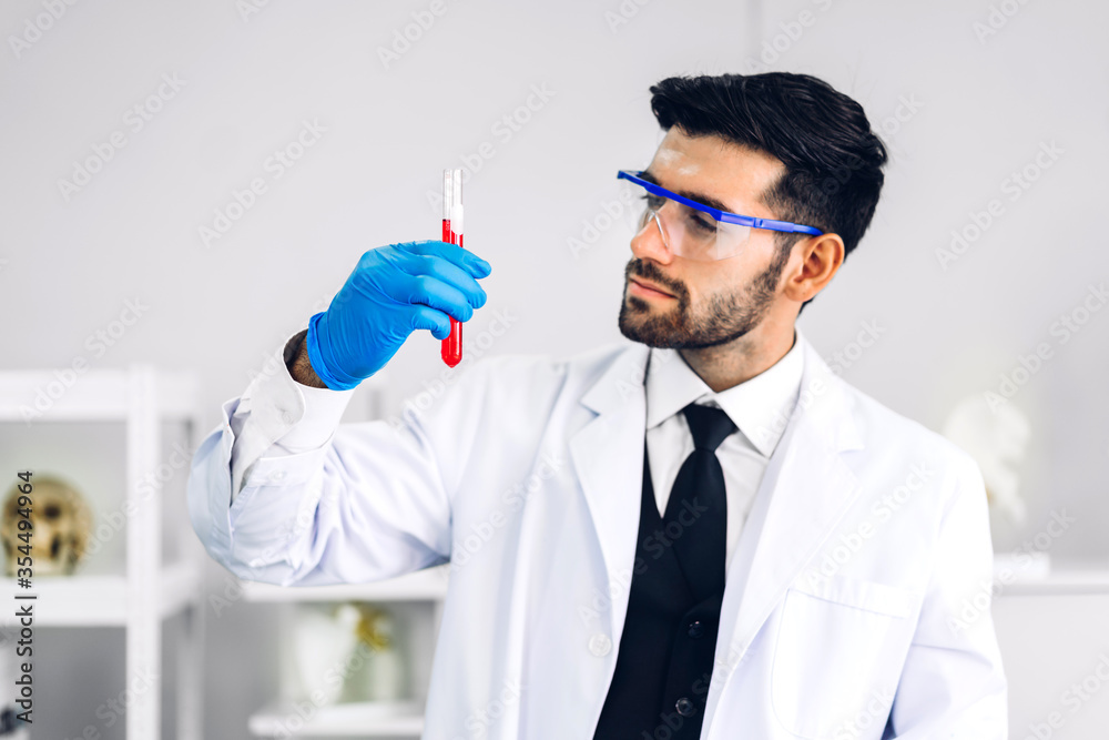 Naklejka premium Professional scientist man research and working doing a chemical experiment while making analyzing and mixing liquid in test tube.Young science man looking sample chemical on glass at laboratory
