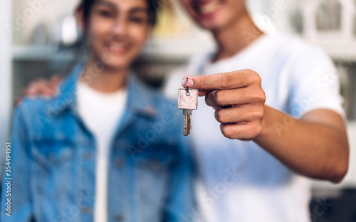 Young family excited happy asian couple holding new house key in their hands and buying a new home and are moving together.business and real estate concept