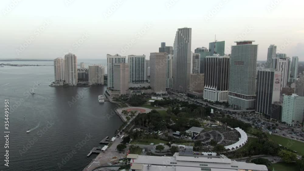 Aerial shot of amphitheatre at park by sea in city against sky, drone flying forward towards skyscrapers during sunset - Miami, Florida Aerial shot of amphitheatre at park by sea in city against sky, drone flying forward towards skyscrapers during sunset - Miami, Florida