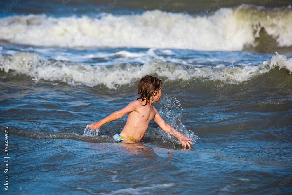 Kid playing on the beach on summer holidays. Happy child playing in the sea. Kid playing on the beach on summer holidays. Happy child playing in the sea.