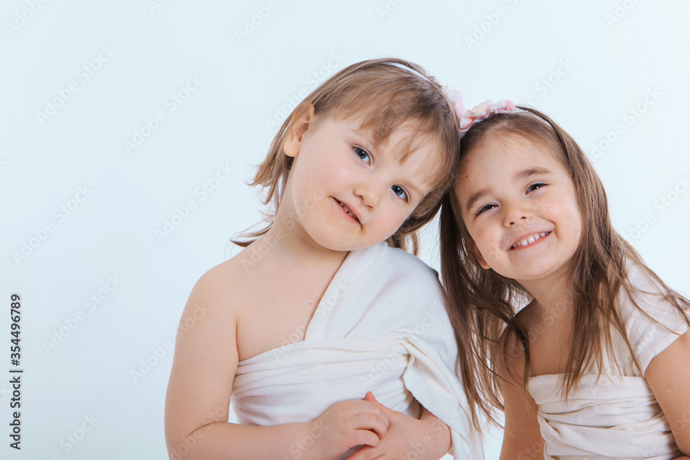 two little happy girls smiling on white background. Portrait of children hugging. The concept of relationships in the family, friends, sisters, couple in love. Copy space two little happy girls smiling on white background. Portrait of children hugging. The concept of relationships in the family, friends, sisters, couple in love. Copy space