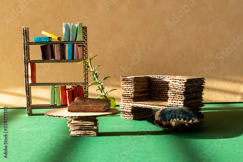 Cardboard furniture for a dollhouse interior. Cardboard sofa, bookcase and table. Room for copy. 