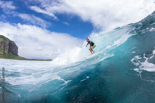 Surfing on big waves against the backdrop of picturesque mountains and beautiful clouds