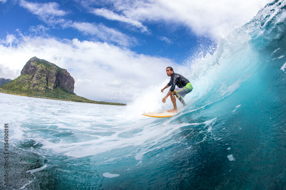 Surfing on big waves against the backdrop of picturesque mountains and beautiful clouds