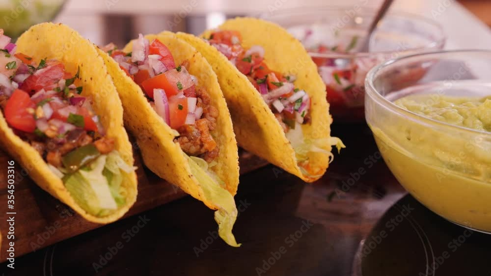 Hard taco shells in wooden holder with all the fillings added - waiting for the guacamole topping, camera orbit, close up - phases of making tacos Hard taco shells in wooden holder with all the fillings added - waiting for the guacamole topping, camera orbit, close up - phases of making tacos