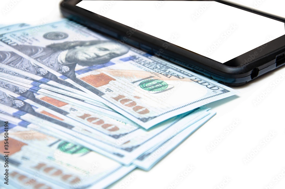 Dollars and smartphone. Banknotes in denominations of 100 dollars lie on a white background on them, next to them lies a smartphone with a white screen. Top view and angle Macro smartphone and dollars Dollars and smartphone. Banknotes in denominations of 100 dollars lie on a white background on them, next to them lies a smartphone with a white screen. Top view and angle Macro smartphone and dollars