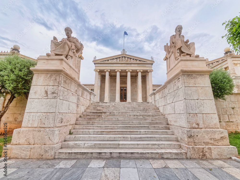 Obraz premium impressive sky over Plato and Socrates the ancient Greek philosophers statues in front of the national academy of Athens, Greece