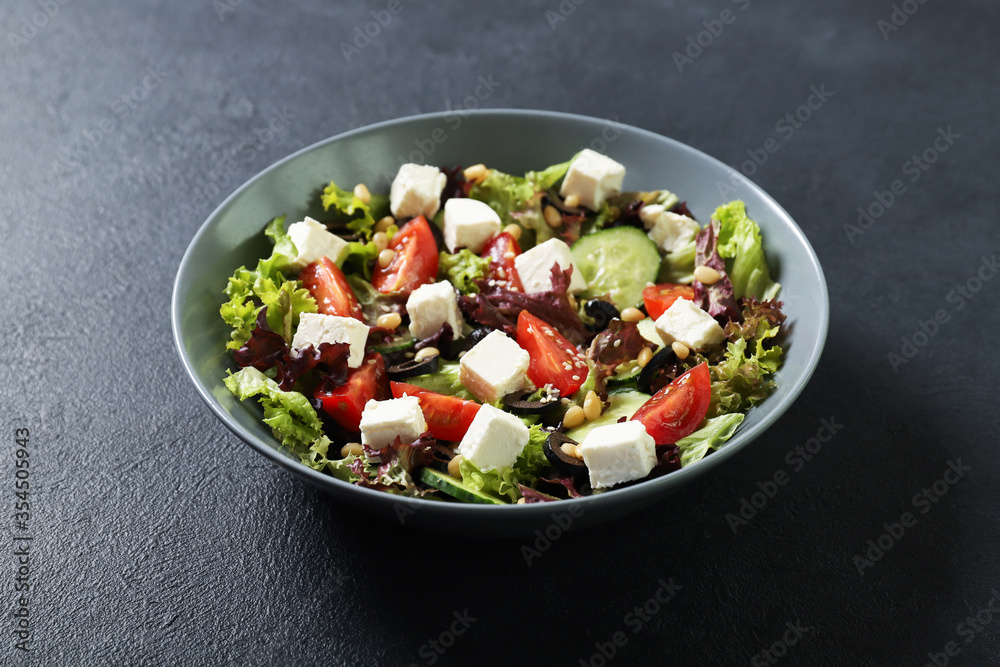 Plate with fresh vegetables salad on a black background. Vegetarian food Plate with fresh vegetables salad on a black background. Vegetarian food