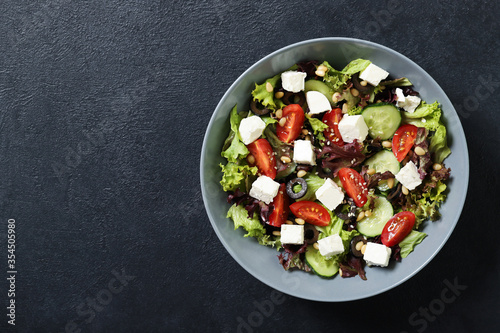 Plate with fresh vegetables salad on a black background. Place for text