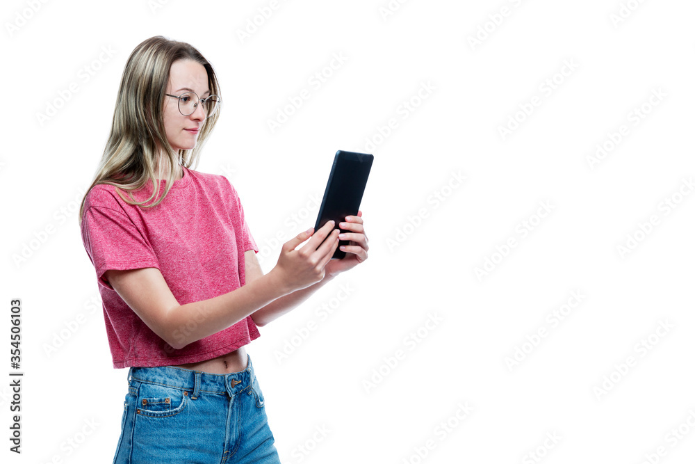 A young girl in jeans with a tablet in her hands. Isolated on a white background. Space for text. A young girl in jeans with a tablet in her hands. Isolated on a white background. Space for text.