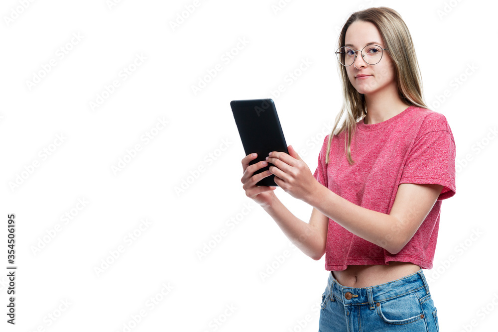 A young girl in jeans with a tablet in her hands. Isolated on a white background. Space for text. A young girl in jeans with a tablet in her hands. Isolated on a white background. Space for text.