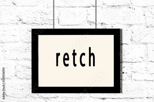 Obraz na plátně Black frame hanging on white brick wall with inscription retch