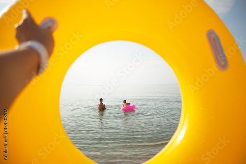 close-up pf woman hand holding th yellow rubber ring and look to the cirkle toe the family swimming in the sea. photo