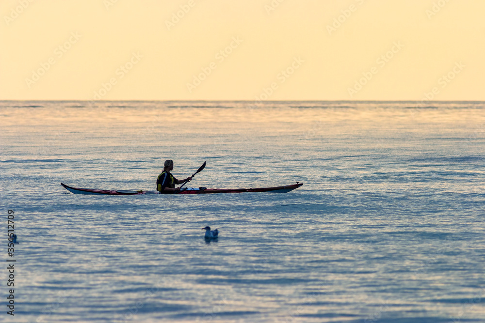 Naklejka premium Kayak paddling at sea in sunset