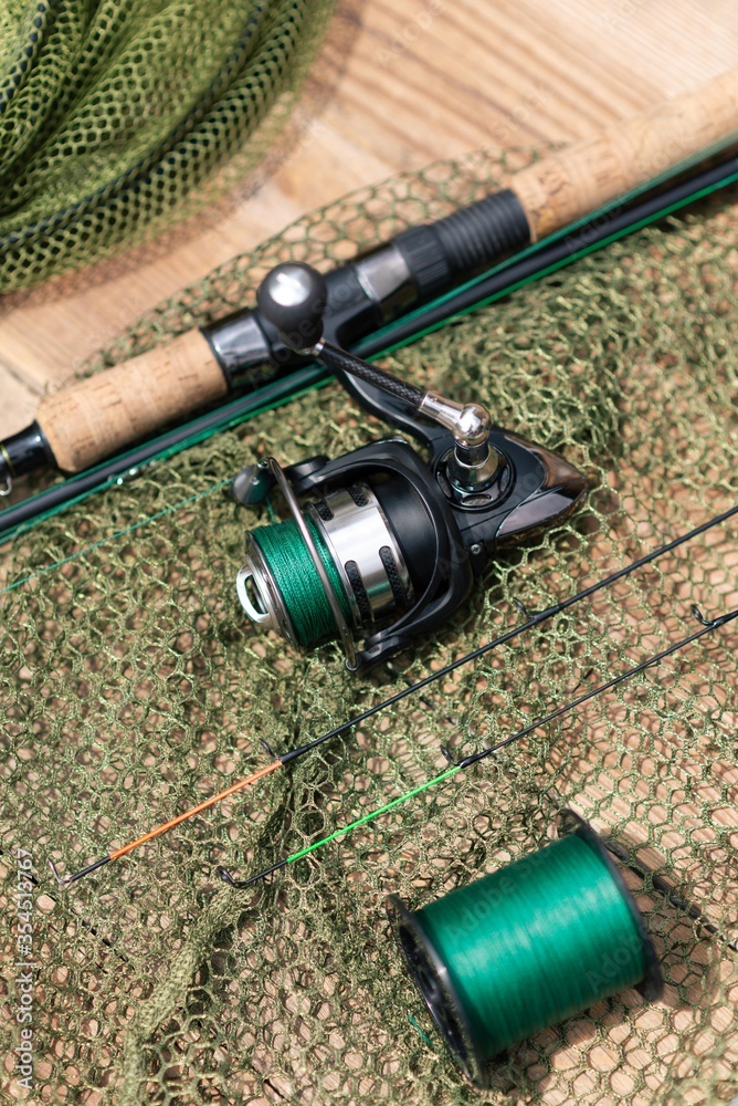 spin fishing rod with reel isolated on wooden table. fishing background. spin fishing rod with reel isolated on wooden table. fishing background.