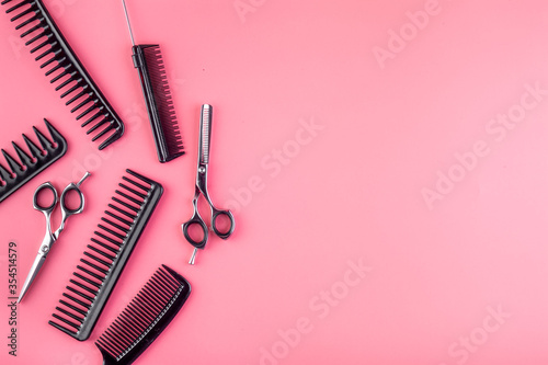 Combs, hairbrush, scissors on pink desk from above copy space